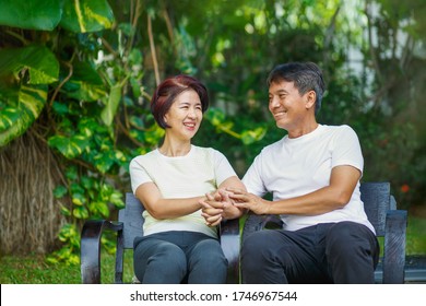 Middle Aged Couple Relax Sitting On Bench In Backyard.