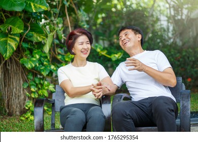 Middle Aged Couple Relax Sitting On Bench In Backyard.