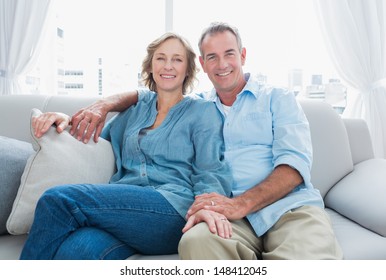 Middle Aged Couple Relaxing On The Couch Smiling At Camera At Home In The Living Room