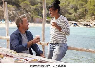 Middle Aged Couple Relaxing On A Jetty By The Sea, Ibiza