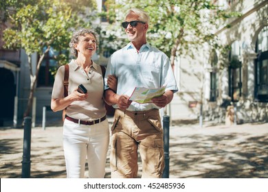 Middle Aged Couple Roaming Around The City Holding A Map. Senior Couple With A Map Walking In The Town.