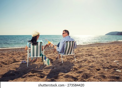 Middle aged couple sitting on deck chairs and enjoying the view of the sea