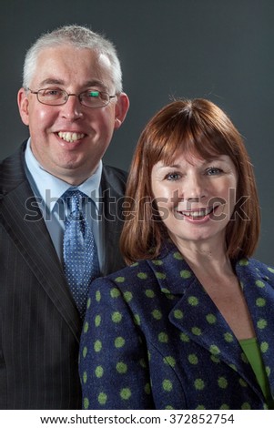 Middle aged couple smile for a conventional flash photography portrait in studio