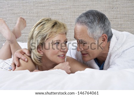 Middle aged couple talking while lying in bed