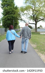 Middle Aged Couple Walking Down The Street Holding Hands, Overweight Woman, Rear View