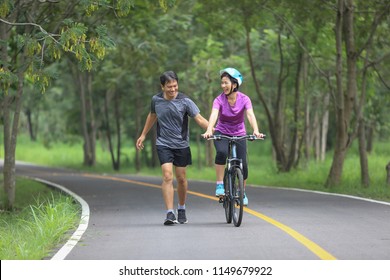 Middle Aged Couple Walking With Their Bicycle In Park