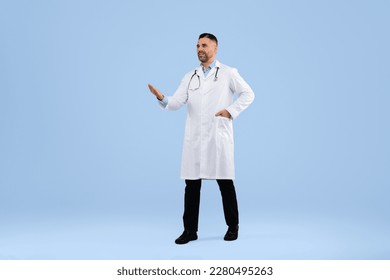 Middle aged doctor man showing copy space with hand, wearing white uniform, walking on blue studio background, full length. Professional general practitioner advertising your text - Shutterstock ID 2280495263