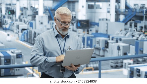 Middle Aged Engineer Monitoring and Analyzing Conditions at an Automated Modern Electronics Factory with Mobility Robots Working with the Help of Artificial Intelligence Software - Powered by Shutterstock