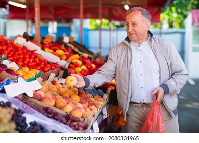 Middle Aged European Man Buying Peaches In Fruit Shop.