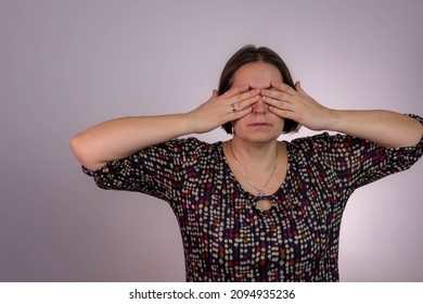 Middle Aged European Woman Hides Her Face, Studio Photo Isolated On Gray Background. She Has Social Phobia, Tying To Be Anonym. Woman Covering Face With Hands.