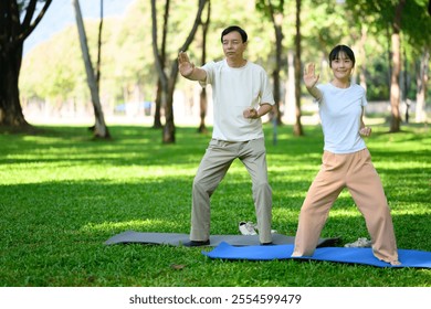 Middle aged father and daughter practicing Tai Chi in serene park. Family activities, health and well being concept - Powered by Shutterstock