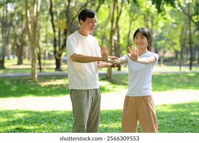 Middle aged father and his adult daughter are enjoying Tai Chi session together in a park - Powered by Shutterstock