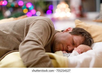 Middle Aged Father Sleeping Near His Newborn Baby Daughter On Christmas. Young Dad Cuddling With Baby Girl At Home. Happy Parenthood, Carefree Childhood, Family, Love. Cute Adorable Baby Sleeping