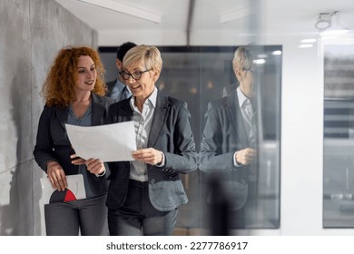 Middle aged female business mentor walking with employees in company - Powered by Shutterstock