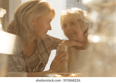 Middle aged female caregiver spending time with older lovely woman