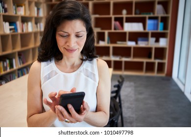 Middle Aged Female Creative Using Smartphone In Office