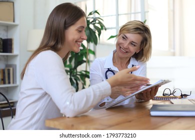 Middle Aged Female Doctor Therapist In Consultation With Patient In Office.