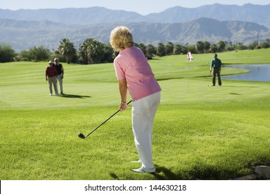 Middle Aged Female Golfer With Friends On Golf Course