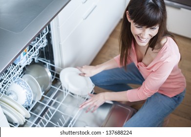 Mädchen mittleren Alters in der Küche mit Geschirrspüler.  Blick auf junge Frau in der Küche, die Hausarbeit macht