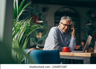 Middle Aged Gray Haired Man Using Cellphone In Cafe Bar