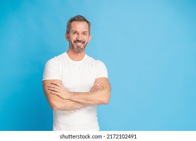 Middle aged grey haired man with standing with arms folded happy smiling on camera wearing white t-shirt isolated on blue background. Mature fit man, healthy lifestyle concept. - Powered by Shutterstock