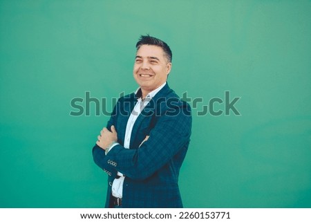 Middle aged handsome man standing crossed arms smiling at camera in solid color background.