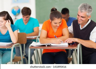 Middle Aged High School Teacher Helping A Student In Classroom