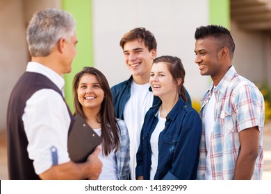 Middle Aged High School Teacher Talking To Students During Break