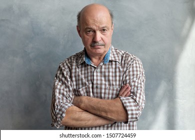 Middle Aged Hispanic Man With Doubtful Expression And Arms Crossed Looking At Camera. Studio Shot