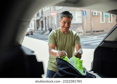 Middle aged hispanic man putting his gym bag in the trunk of the car - Powered by Shutterstock