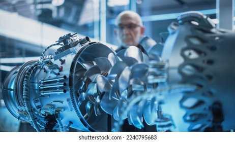 Middle Aged Industrial Engineer Working on a Futuristic Jet Engine, Standing with Laptop Computer in Scientific Technology Lab. Scientist Developing a New Electric Motor in a Research Facility.
