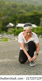 Middle Aged Lady In Sportswear Tying Shoelaces Before Running, Getting Ready For Jogging Outdoors. Healthy Lifestyle, Workout And Wellness Concept