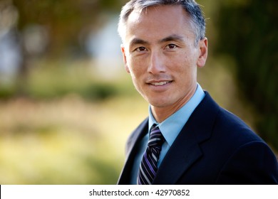 Middle aged male businessman in suit and tie standing outside. Horizontally framed shot.