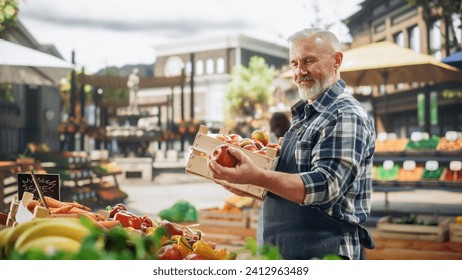 Middle Aged Male Farmer Managing a Small Business on an Outdoors Farmers Market, Selling Sustainable Organic Fruits and Ecological Vegetables. Senior Man Laying Out Ripe Apples on a Food Stall - Powered by Shutterstock