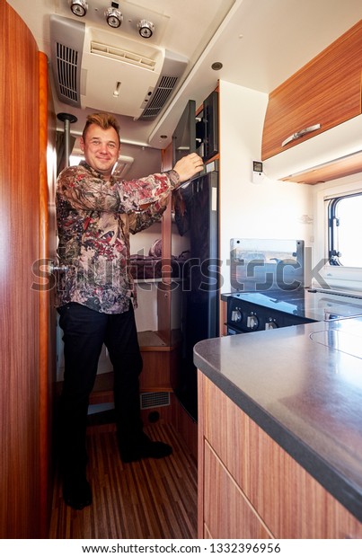 Middle aged\
male standing in the kitchen corner inside of recreational vehicle\
motor home. Travelers journey and adventure, spending time, living\
and traveling in camper van\
concept