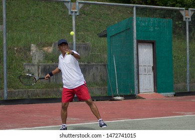 middle aged male tennis player playing tennis at outdoor hard court at day light - Powered by Shutterstock