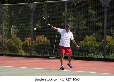 middle aged male tennis player playing tennis at outdoor hard court at day light - Powered by Shutterstock