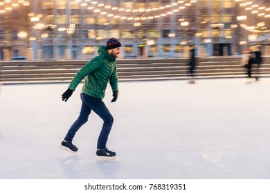 Middle Aged Male Wears Figure Skates, Being At Ice Rink In Winter Park, Has Fun With Friend. Athlete Speed Skater Demonstrates His Talents On Skating Ring. Winter Sport. Christmas Vacations.