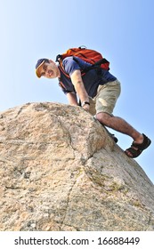 Middle aged man with backpack climbing a rock