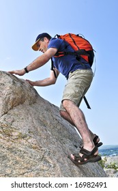 Middle aged man with backpack climbing a rock