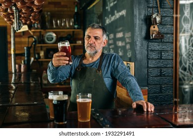 middle aged man bartender serving beer in beer pub - Powered by Shutterstock