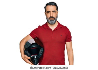 Middle Aged Man With Beard Holding Motorcycle Helmet Thinking Attitude And Sober Expression Looking Self Confident 