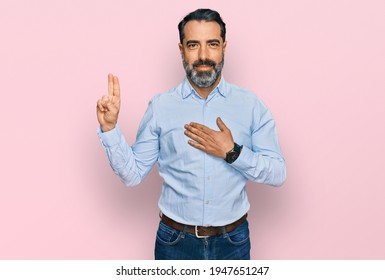 Middle aged man with beard wearing business shirt smiling swearing with hand on chest and fingers up, making a loyalty promise oath 