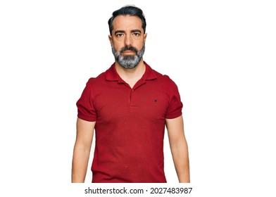 Middle Aged Man With Beard Wearing Casual Red T Shirt With Serious Expression On Face. Simple And Natural Looking At The Camera. 