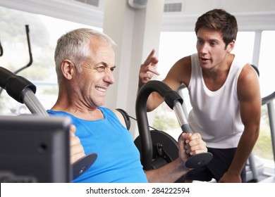 Middle Aged Man Being Encouraged By Personal Trainer In Gym