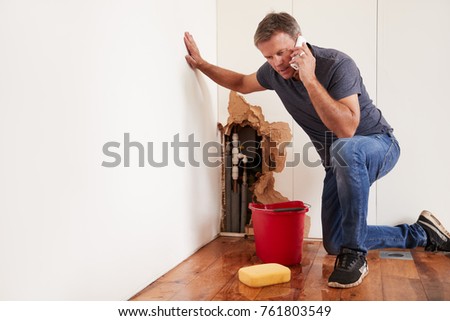 Middle aged man with a burst water pipe phoning for help