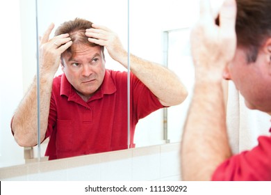 Middle Aged Man Checking For Thinning Hair In The Mirror.