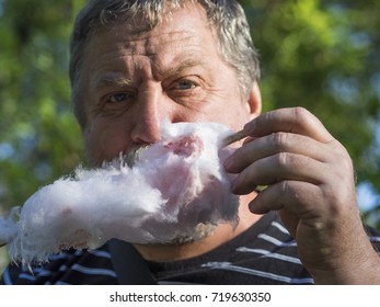 Middle Aged Man Eating A Stick Of Candy Floss Or Cotton Candy Made From Sticky Spun Sugar 