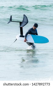 A middle aged man is finishing some foil surfing or hydrofoil surf training in the sea.
