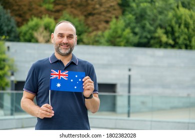 Middle aged man with the flag of Australia against the backdrop of houses and green trees. - Powered by Shutterstock